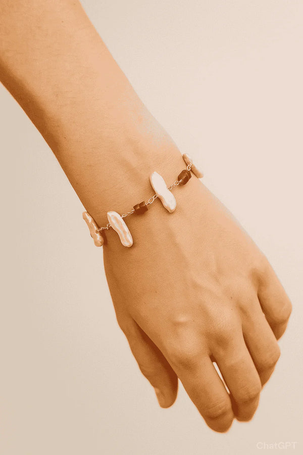 Hand wearing a contemporary bracelet with irregular white pearl and brown stone beads