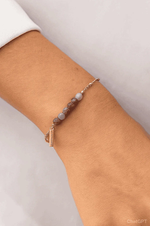 Woman wearing delicate beaded bracelet with gemstone beads and gold chain, modern jewelry
