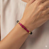 Hand wearing a delicate gold bracelet with pink gemstone beads, modern Indian jewelry