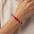 Hand wearing a delicate gold bracelet with pink gemstone beads, modern Indian jewelry
