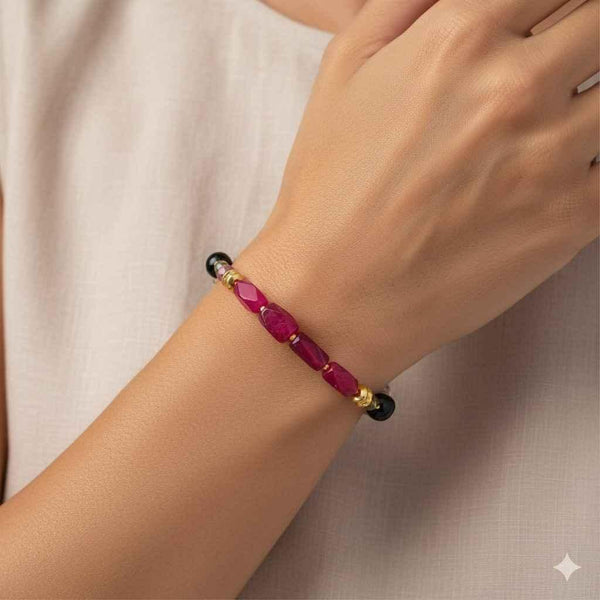 Hand wearing a delicate gold bracelet with pink gemstone beads, modern Indian jewelry