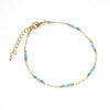 Delicate gold chain bracelet with small blue beads, minimalist jewelry on white background