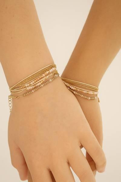 woman wearing layered gold and pastel beaded bracelets on both wrists