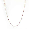 Gold chain necklace with evenly spaced small red beads on white background