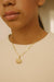 Gold chain necklace with eye-shaped pendant worn on neck, modern jewelry fashion